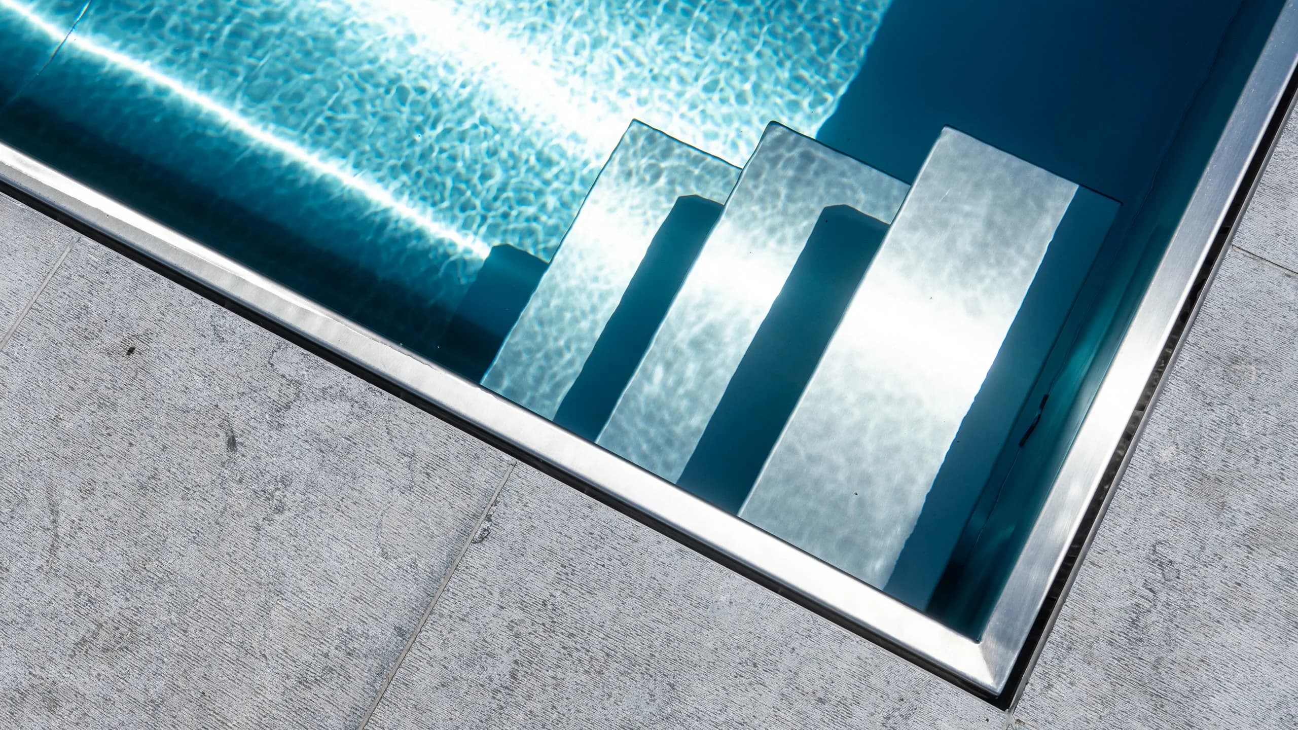 Stainless steel pool steps under crystal clear turquoise water
