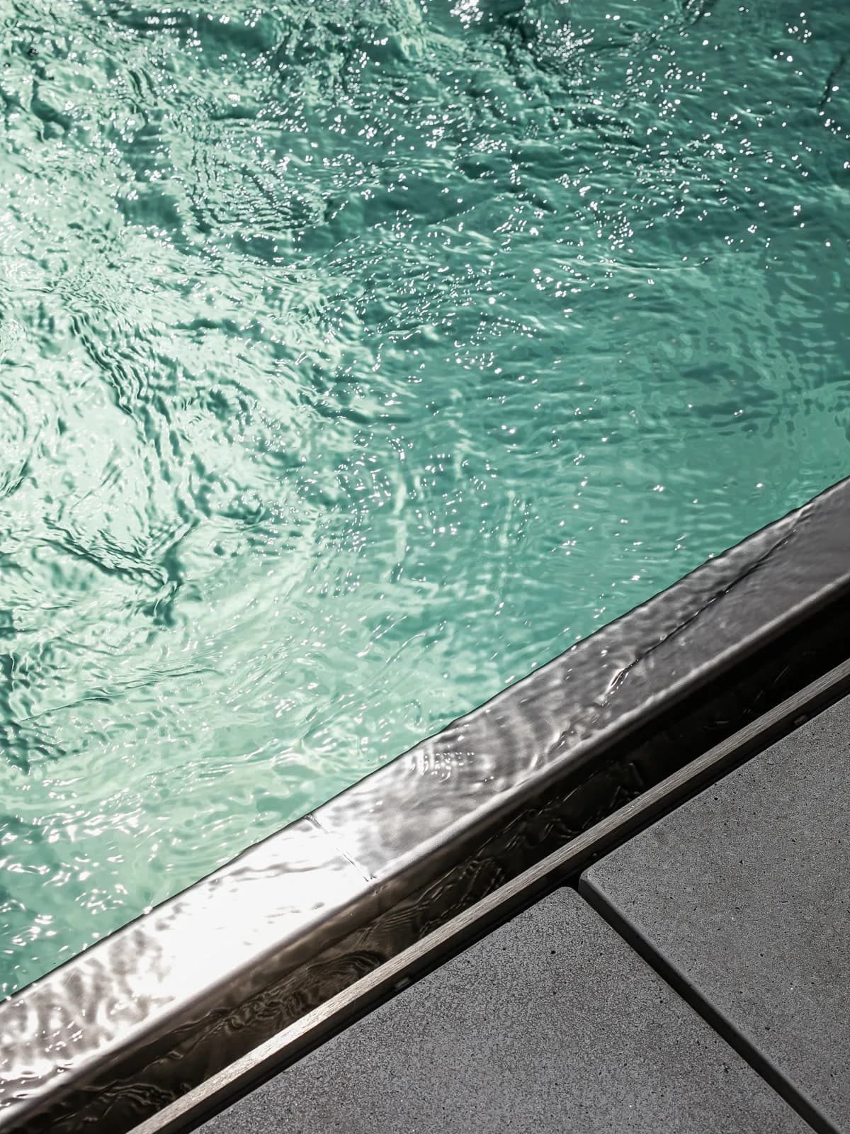 Churning turquoise pool water along a stainless steel edge